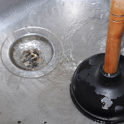 Clogged drain with a plunger in the kitchen sink