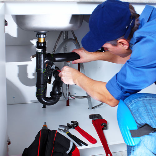 Plumber working on the pipes under the kitchen sink