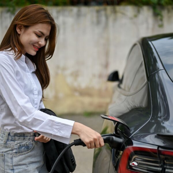 smiling woman charging electric vehicle