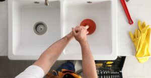 Plumber using a plunger to unclog a sink.