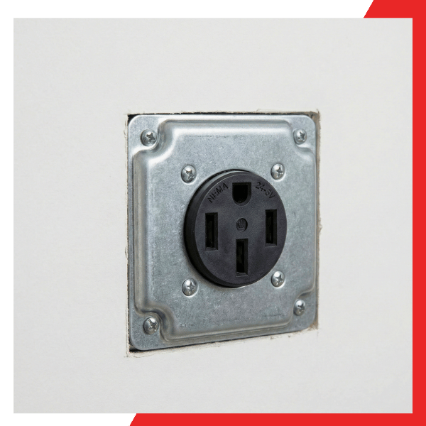 Flush-mounted industrial-grade 240V outlet for electric car charging installed in a clean white wall.